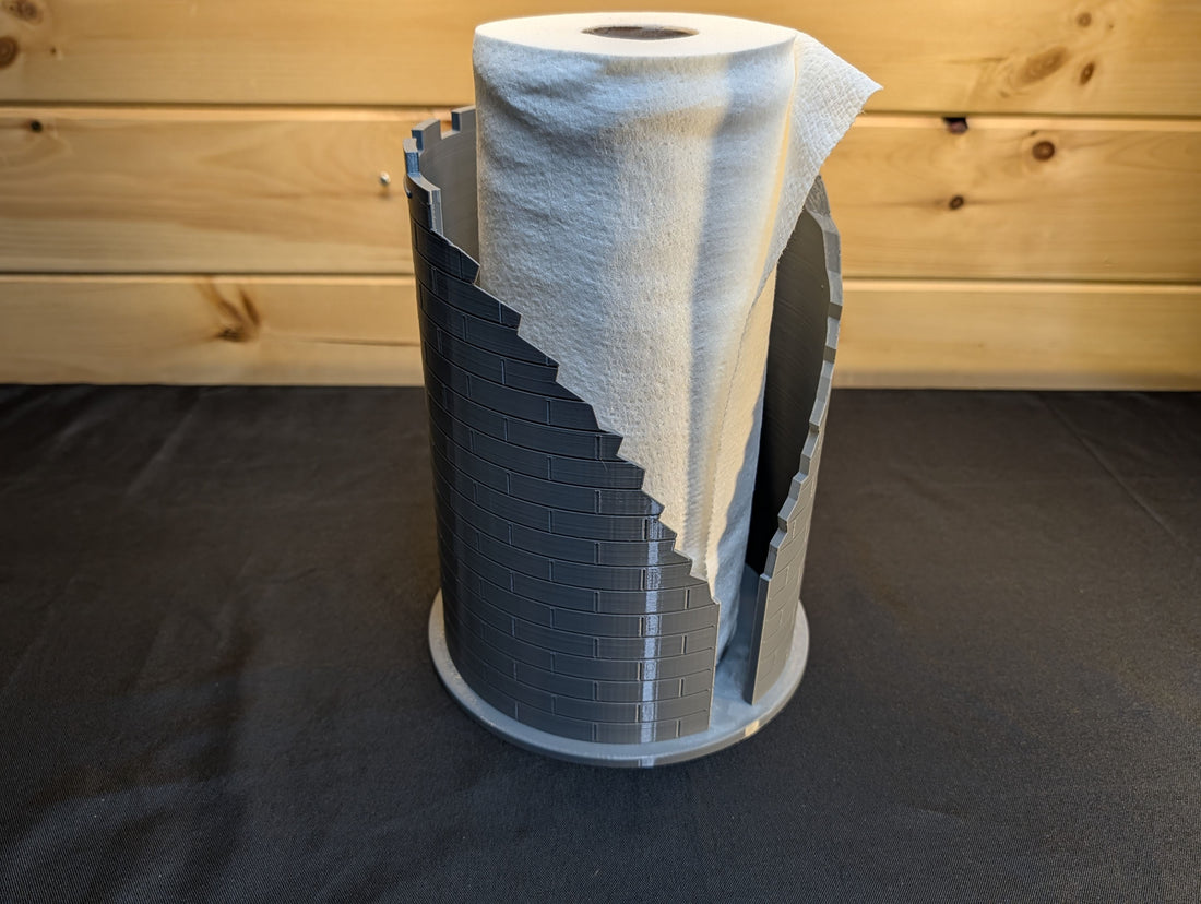 Grey castle ruins paper towel holder with the loose paper end through the stepped opening
