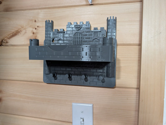 Grey castle wall key holder installed on a wood wall with its tray attached