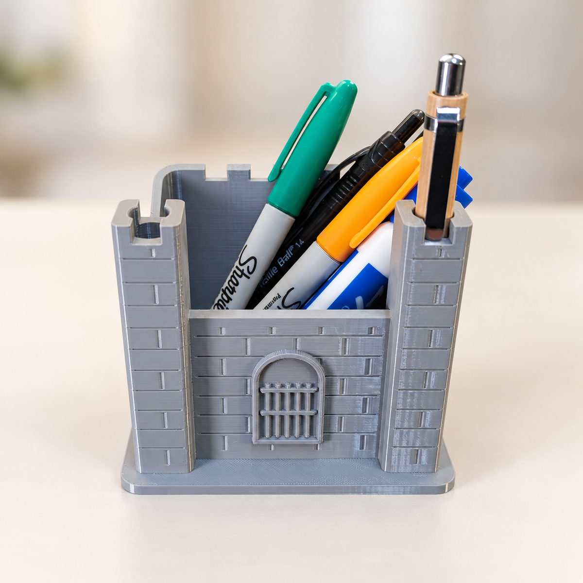 Grey castle pen holder with pens, brick walls and barred gate