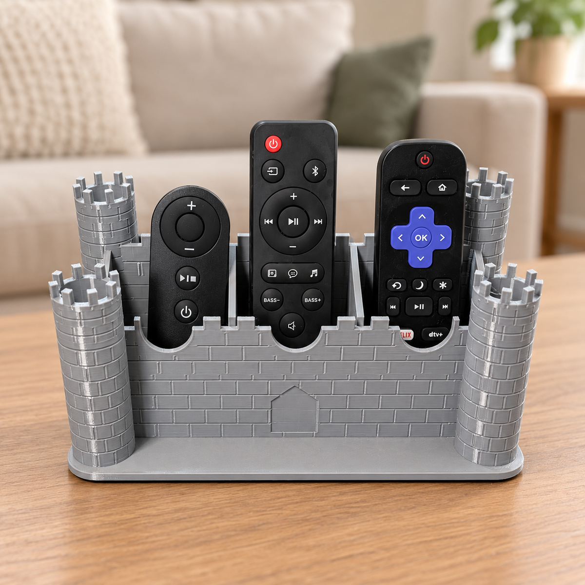 Gray castle remote control holder with three remotes; retouched living room background