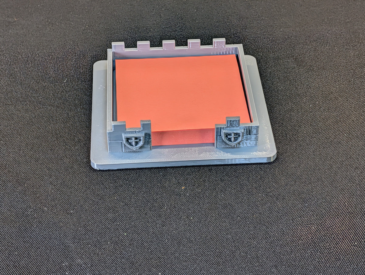 Front view of the actual grey castle sticky-note holder with orange note pad