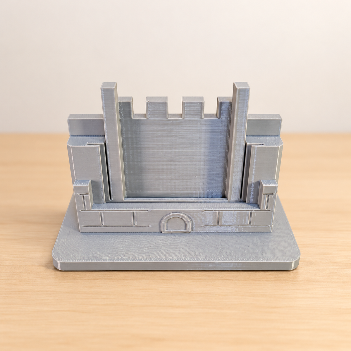 Compact grey castle trading-card stand, empty, with an edited neutral background